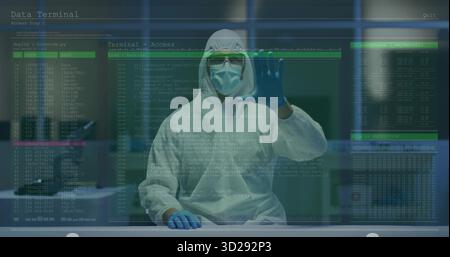 Tecnico di sesso maschile che indossa una tuta protettiva sul banco da laboratorio, con interfaccia con codice olografico Foto Stock