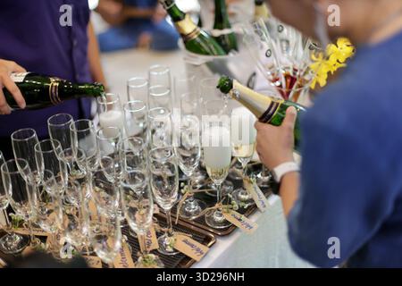 Bicchieri di champagne a fuoco selettivo sul tavolo un drink di benvenuto alcolico viene versato in un bicchiere trasparente. Foto Stock