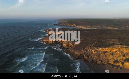 Foto di paesaggio aereo di una splendida costa rocciosa e verde sull'oceano Atlantico nella regione di Alentejo, Portogallo al tramonto. Vista rialzata drone, viaggio Foto Stock