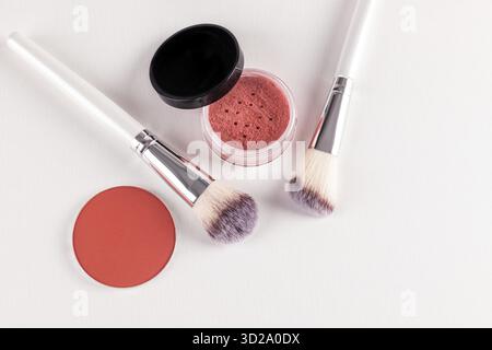 Due eleganti pennelli per il trucco e due blush in un vaso aperto, un blocco tonalità rosa su sfondo bianco goffrato. vista dall'alto. Uno spazio di copia. Il concetto di bellezza Foto Stock