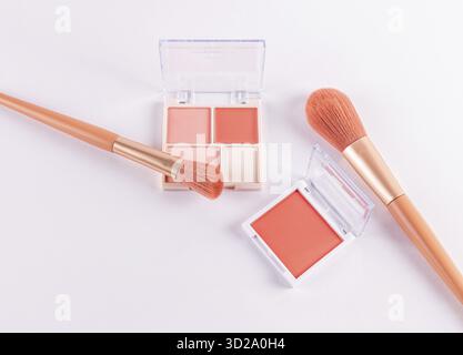 Due confezioni aperte con sfumature color pesca e varie tonalità di luce su sfondo bianco con due pennelli professionali per il trucco. vista dall'alto. spazio per il testo Foto Stock