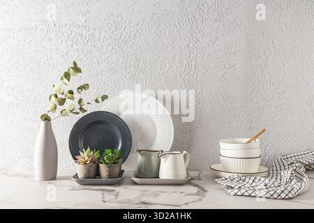 Bello sfondo bianco in stile minimalista cucina con utensili bianchi e fiori interni in pentole di ceramica. Aspetto frontale elegante. uno spazio di copia Foto Stock