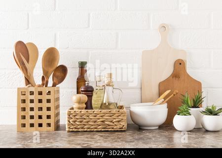Elegante sfondo bianco della cucina con utensili da cucina e piante di casa in vaso verde su un piano di marmo Foto Stock