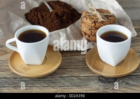 Due tazze di espresso appena fatto su un tavolo di legno. Chicchi di caffè su un tavolo di legno chiaro, stile rustico, fatti in casa Foto Stock