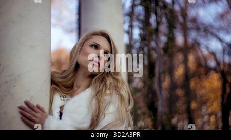 Pelliccia, scena dell'autunno e dell'inverno, bella donna bionda con gesti di malinconia vestita con cappotto grigio Foto Stock