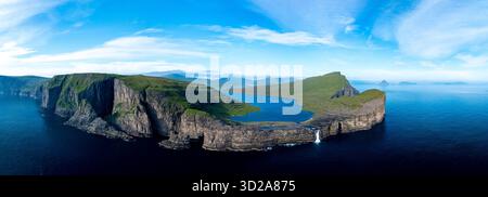 Le maestose scogliere si innalzano drammaticamente dalle acque turchesi delle Isole Faroe, mostrando un panorama mozzafiato. Lago Sorvagsvatn Foto Stock