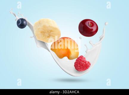 Spruzzi di frullato e frutta in aria su sfondo azzurro Foto Stock