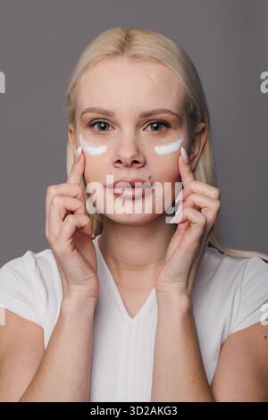 Donna bianca influencer di bellezza applicando patch idrogel sotto gli occhi Foto Stock