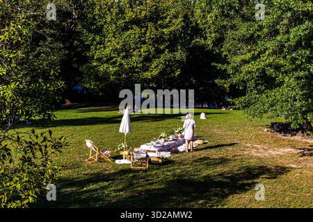 Una donna che prepara un tavolo decorato per un brunch, un picnic o una festa a Central Park, Manhattan, New York City, in un weekend estivo di sole pomeriggio Foto Stock