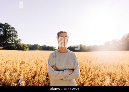 Ritratto di una donna sicura di sé in piedi con le braccia incrociate nel campo Foto Stock