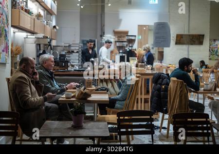 Le persone si siedono all'interno di un affollato caffè situato lungo Piccadilly, nel cuore di Mayfair, Londra, Inghilterra, Regno Unito Foto Stock