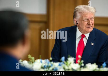 Il presidente Donald J. Trump partecipa a un incontro bilaterale a Busan, Corea del Sud, indossando un auricolare per la traduzione durante le discussioni con il presidente cinese Xi Jinping. 30 ottobre 2025. Per gentile concessione della Casa Bianca. Foto Stock