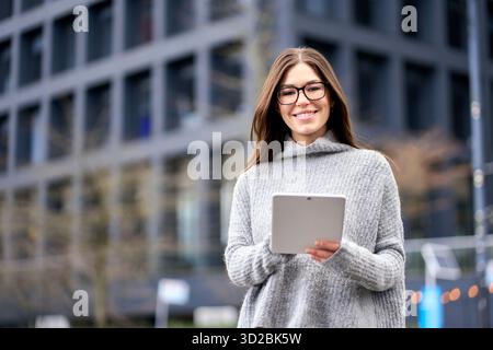 Giovane donna d'affari felice o studente in piedi in città con un tablet digitale. Foto Stock