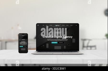 Laptop e smartphone che mostrano un'interfaccia reattiva per il sito Web dell'agenzia creativa su una scrivania luminosa in un elegante ufficio minimalista con sfondo neutro Foto Stock
