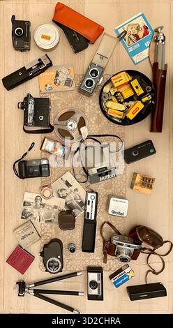 Collezione storica di antiche fotocamere analogiche d'epoca disposte sul tavolo insieme a un vecchio catalogo di cavalletti fotografici Foto Stock