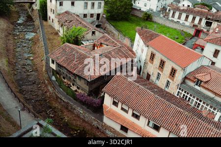 Vista aerea della città vecchia spagnola di Salas nelle Asturie con tradizionali tetti in tegole di argilla, stretti vicoli e piccolo canale fluviale circondato da mura di pietra A. Foto Stock