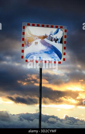 La strada si specchia contro il cielo spettacolare con due persone che camminano verso di essa in silhouette. Nessuna persona riconoscibile nella foto. Foto Stock