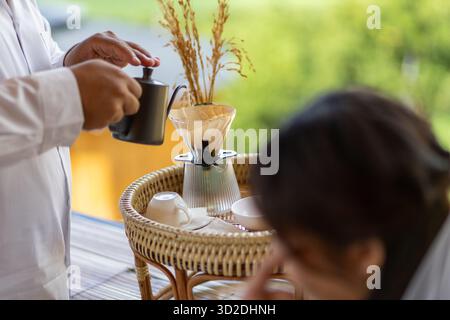 Concentrazione selettiva sul gocciolatoio di caffè. Versare acqua nel gocciolatoio. Foto Stock