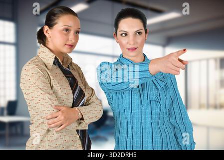 Due donne sono in piedi in una stanza, una che indica qualcosa. La scena è spensierata e giocosa, mentre le donne fanno uno scherzo o indicano qualcosa Foto Stock