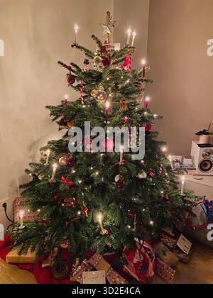 Albero di Natale con candele accese, palle di natale e molti regali avvolti durante le festività natalizie, decorazione moderna, foto di scorta Foto Stock