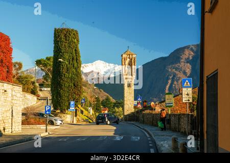 Strada asfaltata lungo la costa da Como a nord e alto campanile di chiesa cattolica. Le persone che si svegliano NOI facciamo anche escursioni con l'etnia cinese Foto Stock