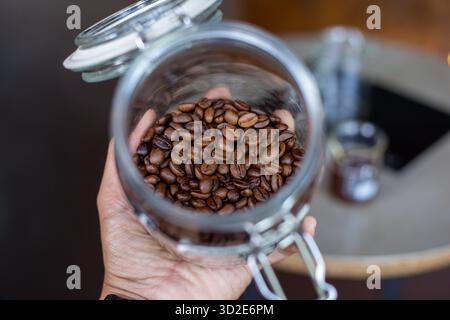 Messa a fuoco selettiva, chicchi di caffè di buona qualità, lucido, marrone scuro in un vaso di vetro. Foto Stock