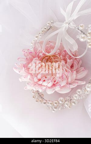 Una decorazione elegante di perle e nastri nell'acconciatura della sposa su un velo bianco con un grande fiore rosa. Vista verticale. concetto del matrimonio Foto Stock