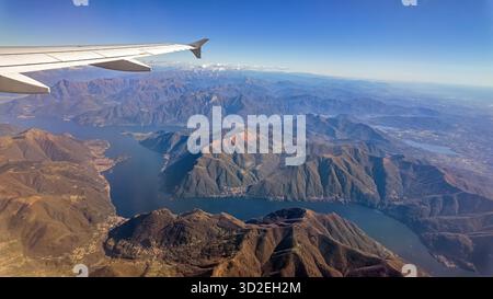 Foto aerea panoramica che mostra il Lago maggiore e il paesaggio montano scattate dalla finestra dell'aereo in una giornata limpida Foto Stock