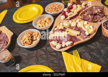 Salumi festivi con formaggi, affettati, cracker e olive su tavola e ciotole di legno, pronti per essere condivisi a una festa informale o con catering gath Foto Stock