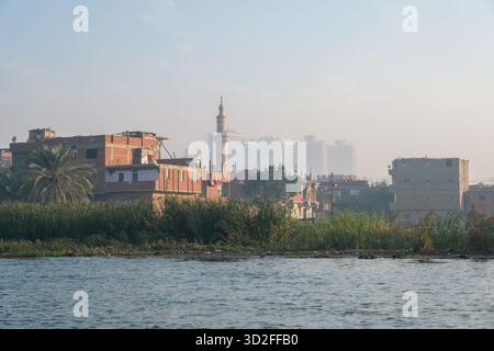 Moschee ed edifici in mattoni rossi sul Nilo con lo skyline del Cairo visibile sullo sfondo, Cairo, Egitto Foto Stock