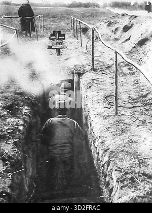 Da le Miroir, ottobre 1915, questa fotografia mostra i soldati francesi che entrano in una trincea appositamente costruita durante la prima guerra mondiale. Contrassegnata con "Entrée", è stata utilizzata per esperimenti con maschere protettive contro il gas velenoso. Dopo l'introduzione della guerra chimica, l'esercito francese testò i respiratori e addestrò le truppe nella sopravvivenza del gas. L'immagine illustra l'adattamento alle nuove minacce e la rapida evoluzione delle misure difensive sul fronte occidentale. Foto Stock