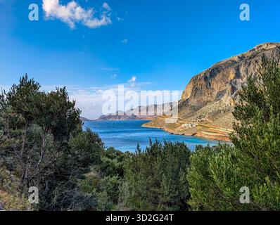 Il Mar Egeo Blu riflette la luce del sole e mostra la Baia di Arginonta circondata da ulivi sotto Un cielo radioso sull'isola di Kalymnos in GR Foto Stock