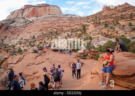 I visitatori si riuniscono sul terreno roccioso vicino all'Angel's Landing, ammirando vedute panoramiche delle pendici di arenaria e del paesaggio desertico. Foto Stock