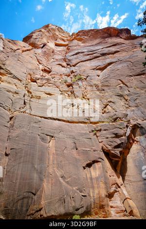 Le calde scogliere di arenaria si innalzano bruscamente sotto un cielo azzurro, mostrando spettacolari motivi verticali, texture desertiche a strati e aspre formazioni geologiche Foto Stock