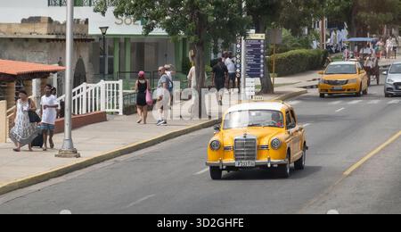 Varadero, Cuba - 2 settembre 2023: Taxi Mercedes-Benz 180 W120 giallo e altri taxi nelle strade di Varadero, Cuba, turisti intorno Foto Stock