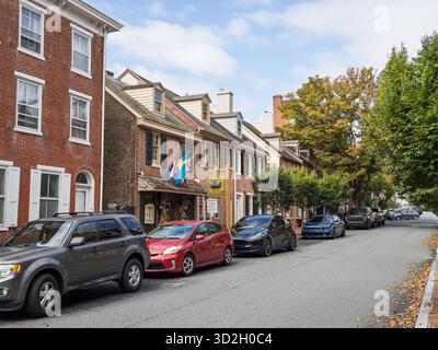 Una fila di storiche case coloniali in mattoni rossi fiancheggiano una strada a New Castle, Delaware, con varie auto moderne parcheggiate lungo il marciapiede in una giornata di sole. Foto Stock