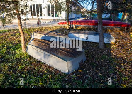 Barche a remi in legno giacciono a terra all'ombra degli alberi. Foto Stock