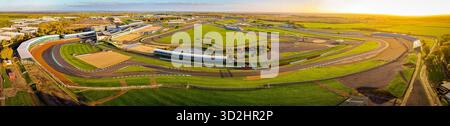 Vista aerea del circuito di Silverstone alla luce del mattino presto, con tribune, edifici a cielo aperto e tracciato della pista. Ideale per gli sport motoristici Foto Stock