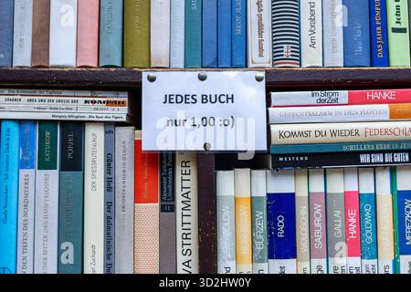 Scaffale di libri di seconda mano in una libreria antiquaria tedesca, che mostra file di libri in lingua tedesca e un'offerta scritta a mano. Foto Stock