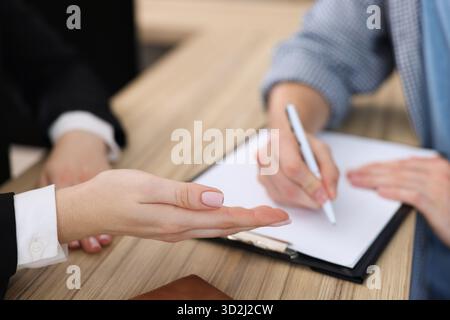 L'addetto alla reception lavora con gli ospiti al banco della reception dell'hotel, primo piano Foto Stock