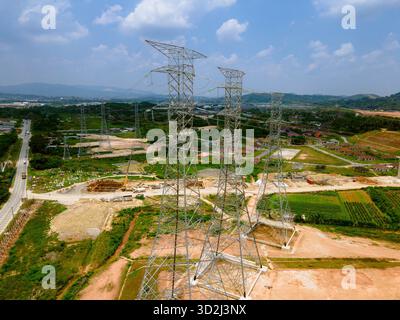 Vista aerea e terrestre delle torri di trasmissione ad alta tensione nella Malesia rurale, che mostra l'infrastruttura elettrica e la rete di distribuzione dell'energia. Foto Stock
