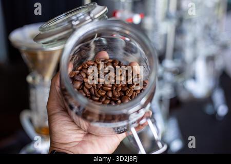 Messa a fuoco selettiva, chicchi di caffè di buona qualità, lucido, marrone scuro in un vaso di vetro. Foto Stock