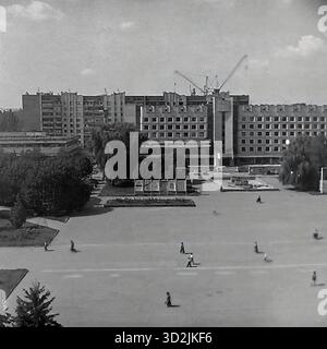 Archivio foto in bianco e nero da Sloviansk, Ucraina, luglio 1997. Questa vista ad alto angolo mostra la piazza centrale della città, Piazza della Rivoluzione d'ottobre (ora Piazza Soborna). La grande piazza aperta ha diversi pedoni che camminano attraverso di essa. Sullo sfondo si trova il massiccio edificio modernista sovietico del Consiglio comunale (Gorsovet). Grandi gru da cantiere sono visibili all'orizzonte dietro l'edificio. Questa immagine cattura il centro amministrativo della città post-sovietica. Foto Stock