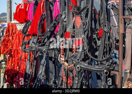 Accessori per carrozze trainate da cavalli in pelle impilati per la vendita su uno stand del mercato, con messa a fuoco morbida Foto Stock