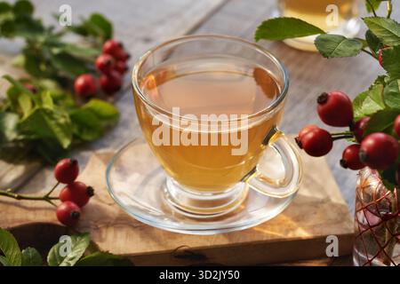 Una tazza di tè all'anca con rose su un tavolo di legno Foto Stock