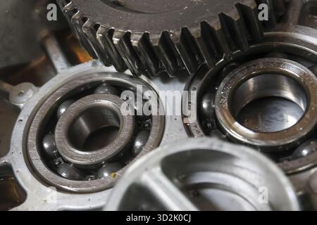 Primo piano di componenti meccanici in metallo arrugginito, con cuscinetti a sfere e ingranaggi. i dettagli intricati evocano un senso di complessità industriale e di lavorazione obsoleta Foto Stock