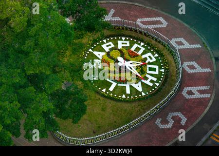 Una vista aerea dall'alto angolo dell'iconico orologio a fiori nel Parco odori, Sapporo, Giappone. La faccia dell'orologio è formata da fiori bianchi e gialli con la mano rossa Foto Stock
