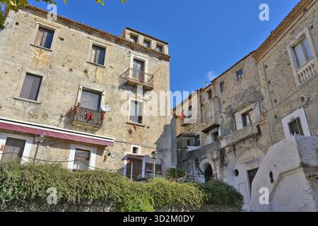 Vecchi edifici storici che costeggiano una strada affascinante a Scalea. L'architettura del villaggio di Scalea mostra il tradizionale fascino italiano sotto un cielo blu luminoso. Foto Stock