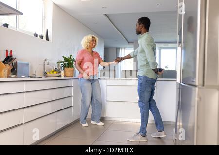 Ballare con gioia, coppia afroamericana in cucina moderna, divertirsi insieme. Felicità, stile di vita, relazione, legame, celebrazione || modello rilasciato Foto Stock