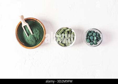 Tre contenitori con diversi tipi di polvere di spirulina naturale, capsule, compresse su sfondo bianco. Disintossicazione. Multivitaminico. supercibo Foto Stock
